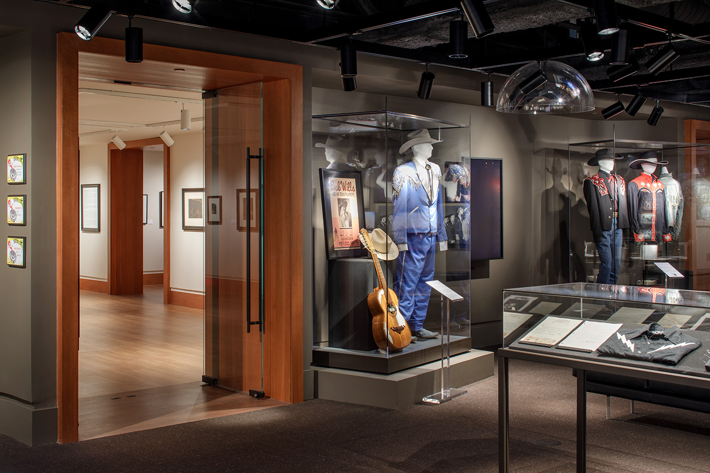 Mannequins dressed in historic western outfits in glass display cases at an exhibit.