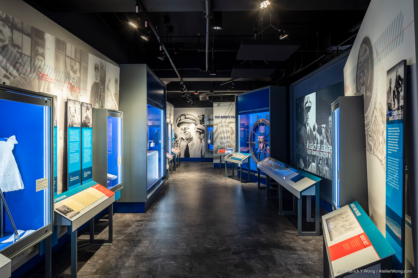 A long exhibit hallway with graphic walls, display cases, and many plaques.