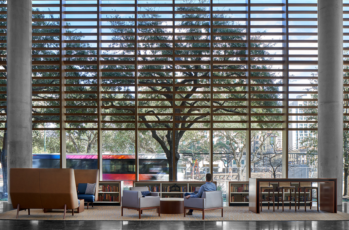 A seating area with low book shelfs that look out to a street.