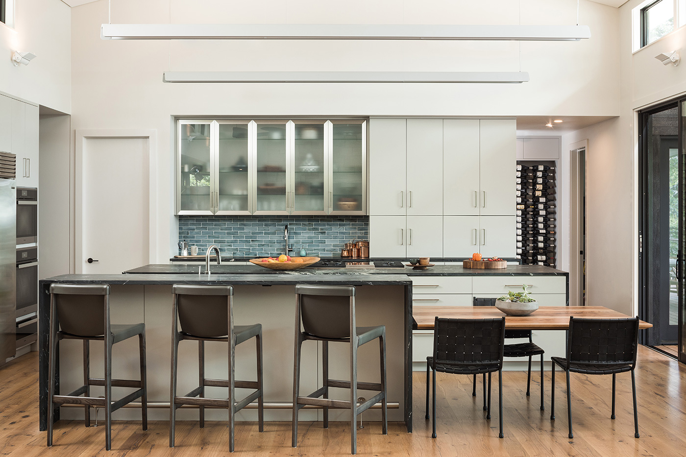 Modern kitchen with high ceilings and stools at counter.