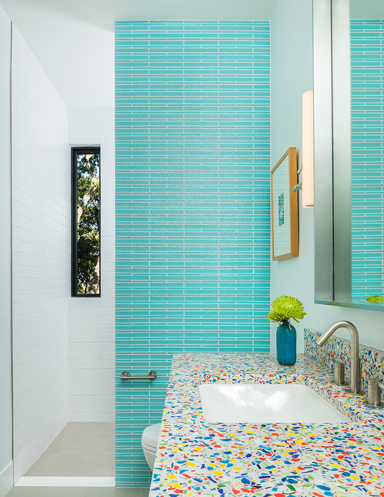 Bathroom with blue tile wall and colorful granite counter.