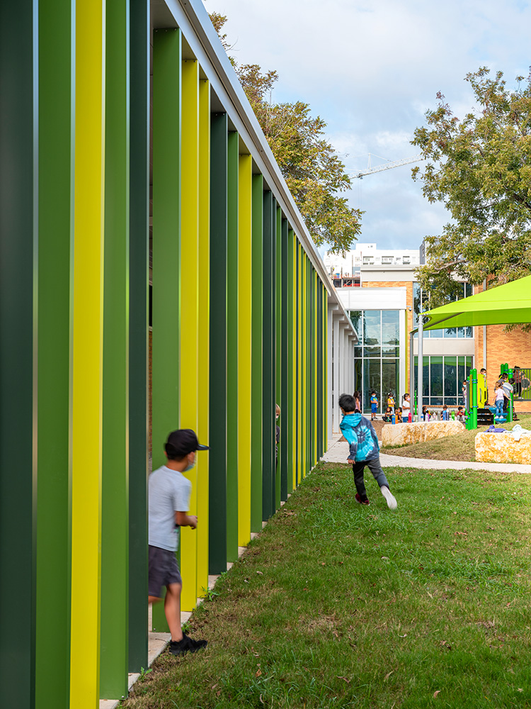 Kids playing outside of a school with a colorful green fence.