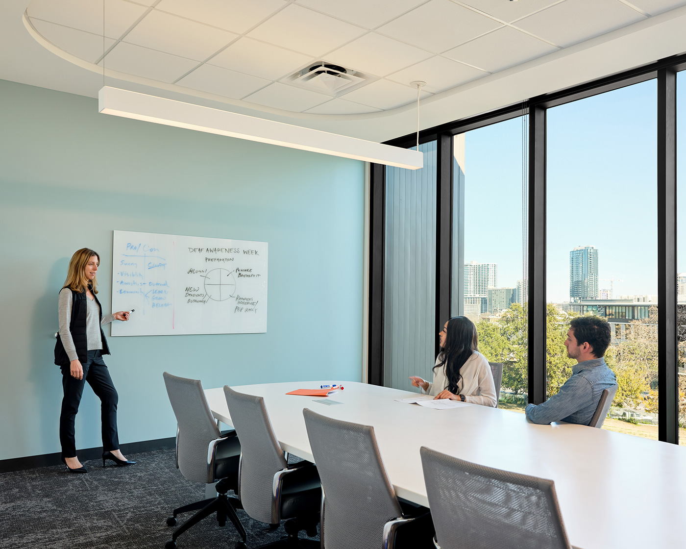 Small meeting in a sleek conference room with floor to ceiling windows.