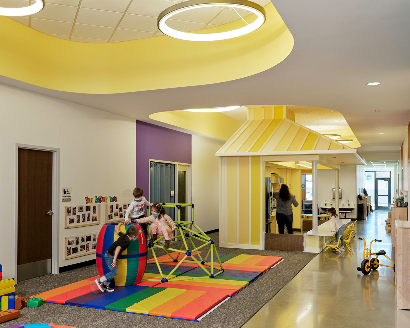 Kids playing in a white and yellow room of a school.