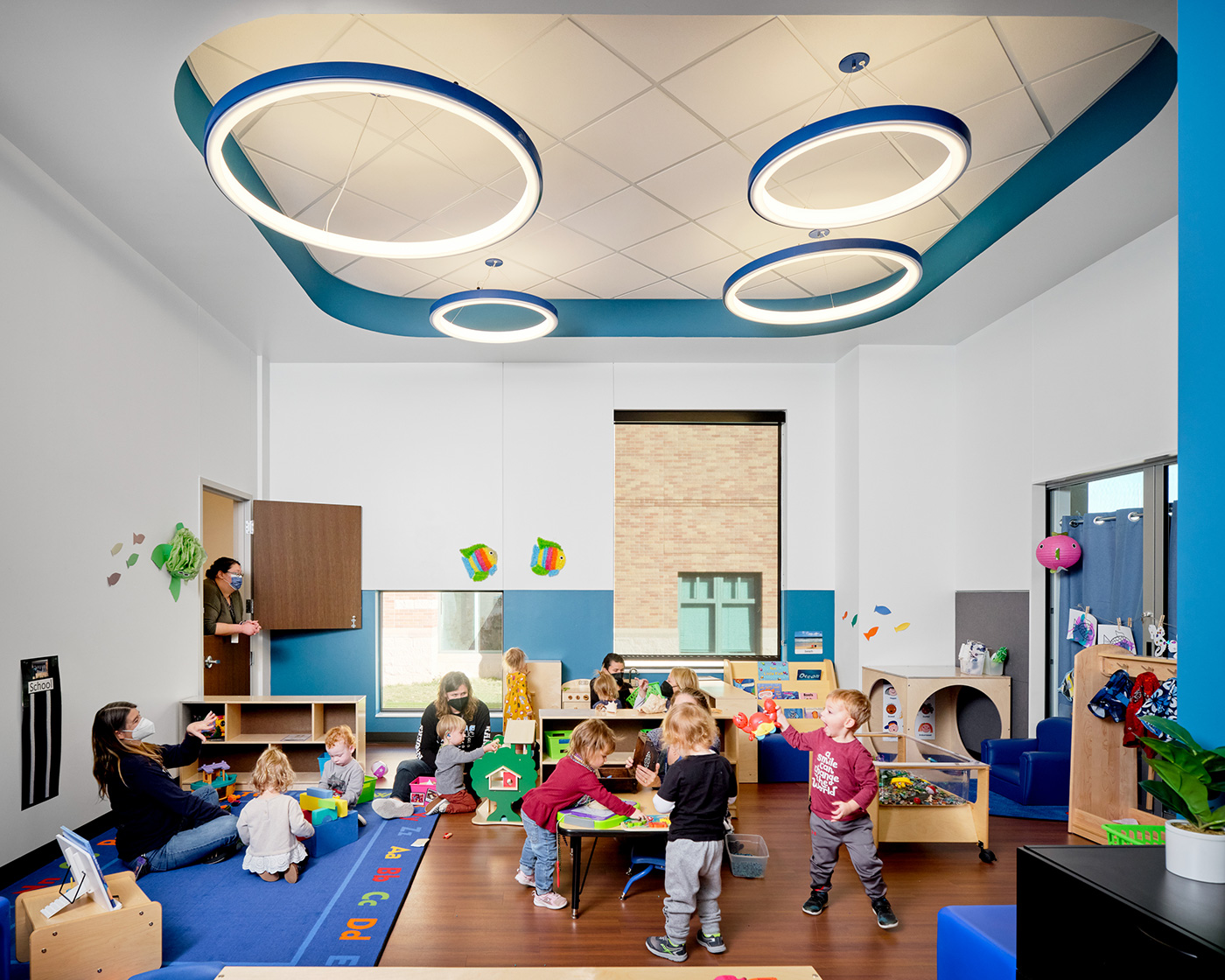 Kids playing om a blue and white classroom.