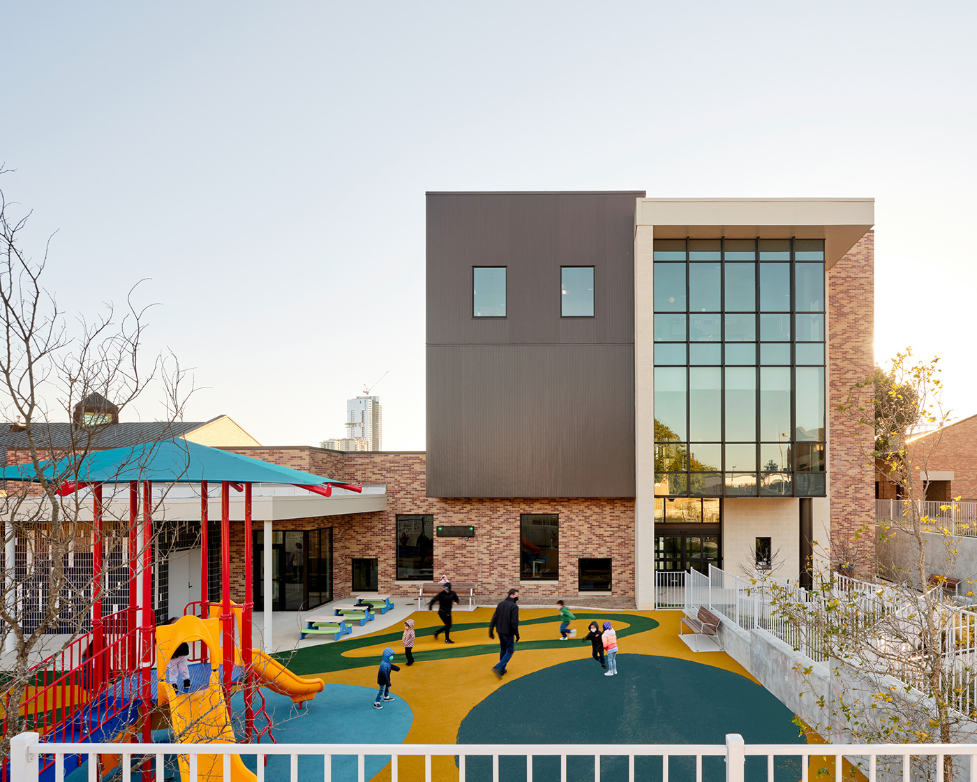 children playing in small playground connected to a building.