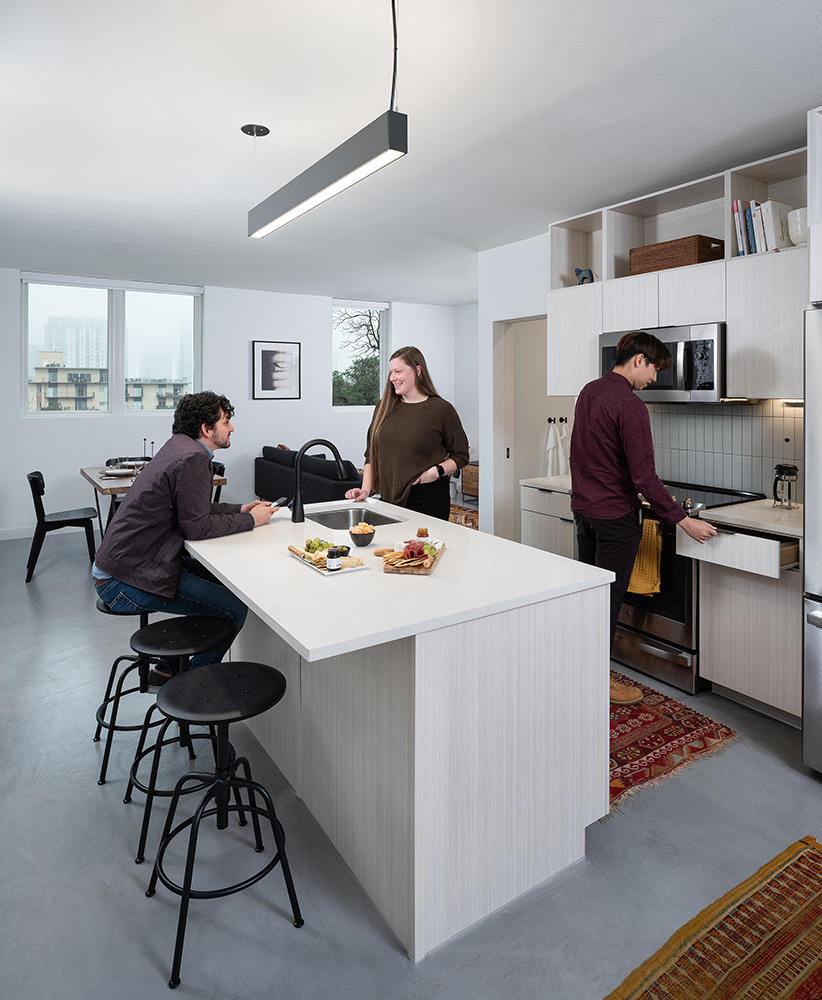 three people talking an snacking in a modern kitchen.