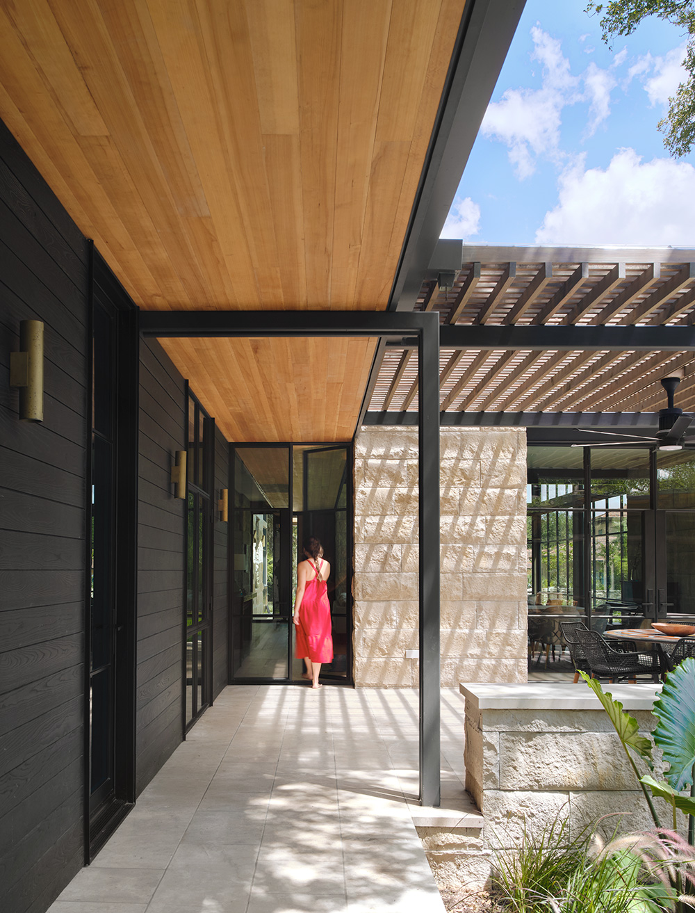 A women walking into a house through its stone backyard patio.