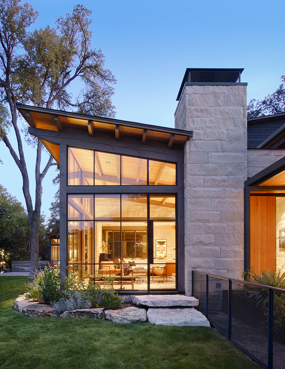 A bright living room visible from the outside of a house through its large windows.