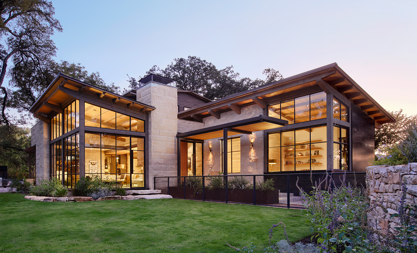 A home at dusk and its surrounding lush landscaping.