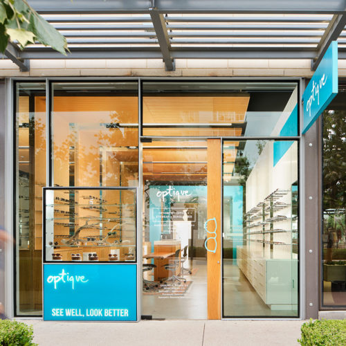 The glass facade of a glasses store in an outdoor mall.