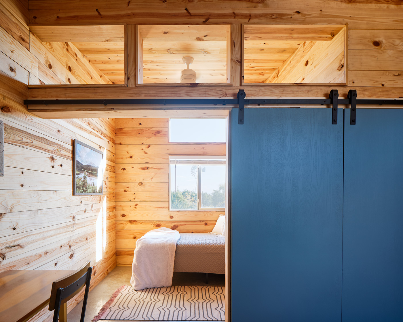 A small wooden bedroom with a sliding door.