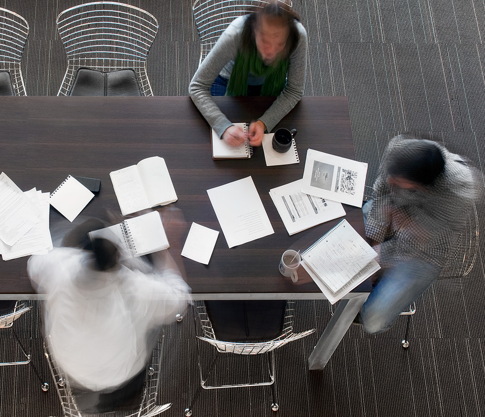 Image from above if three people working together at conference table.