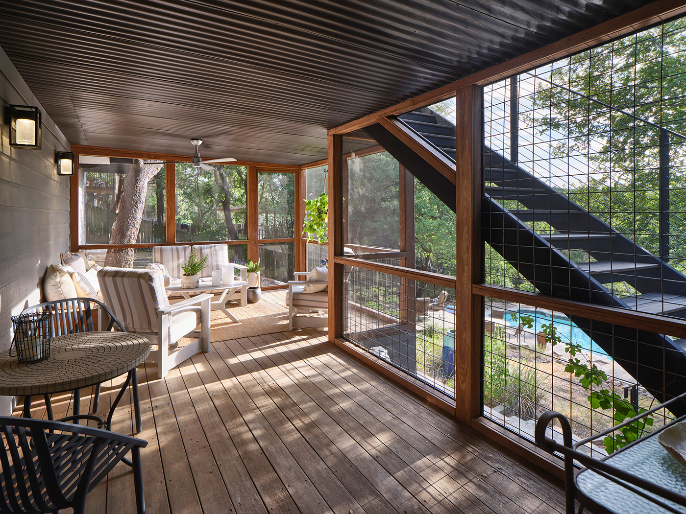 Screened in outdoor deck seating area that looks out to backyard pool.