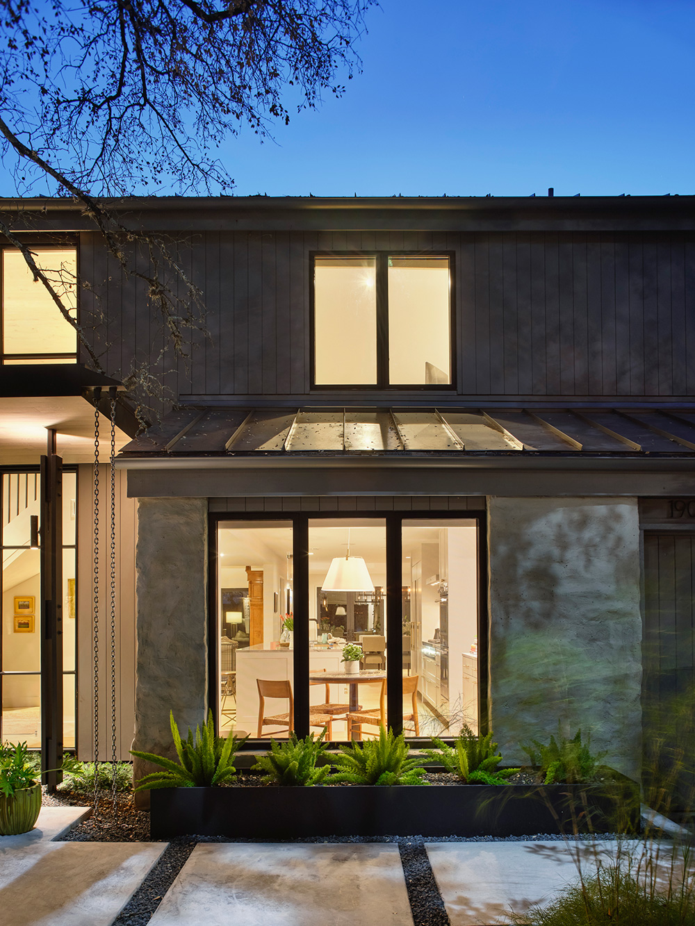 View of lit Livingroom through a front yard window at dusk.