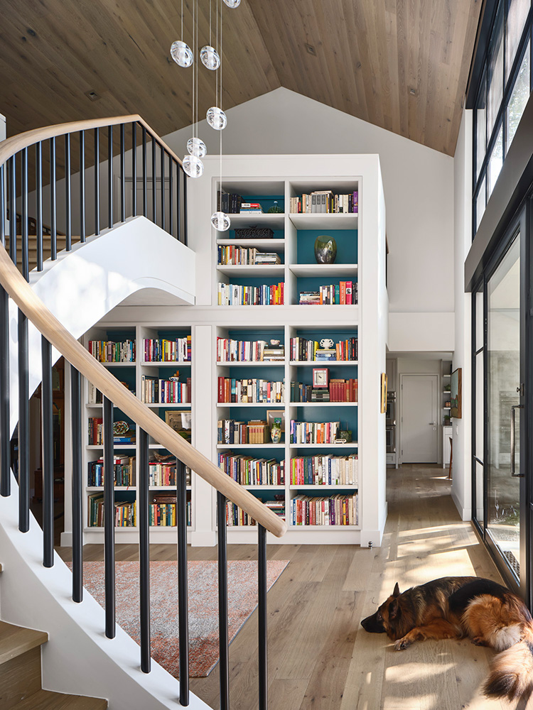 Large bookshelf next to staircase of a home.