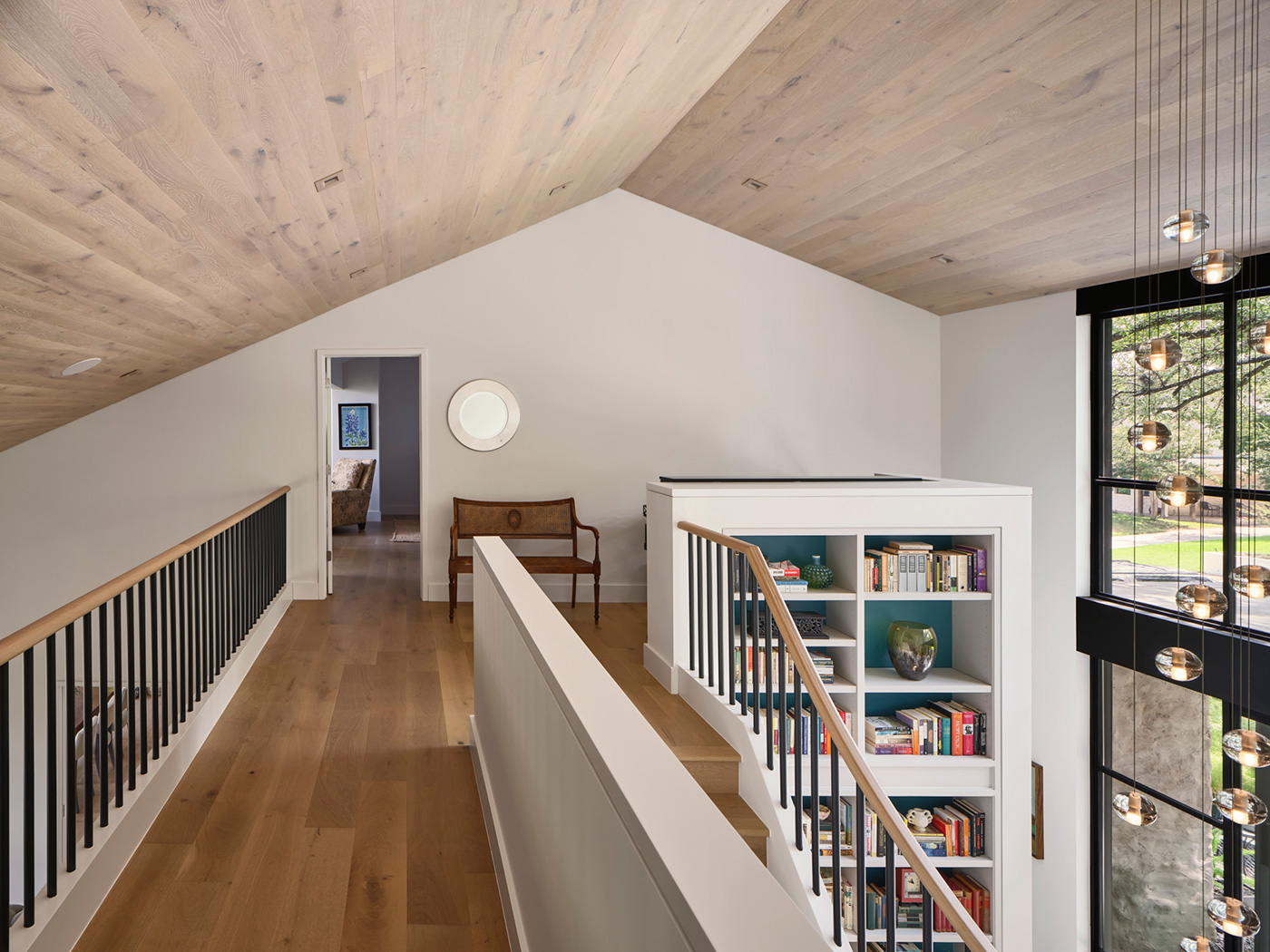 Open upper floor walkway of white home with slanted roofs.