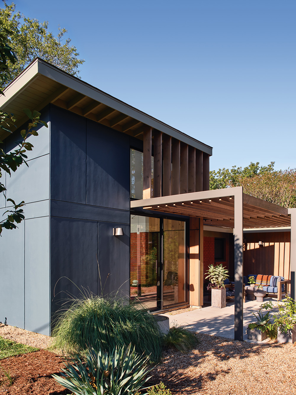 Corner view of the exterior of a house and its surrounding patio and plants.