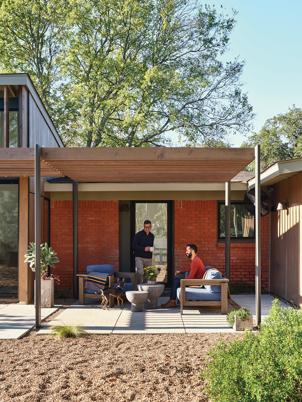 Two people in covered patio area against home.