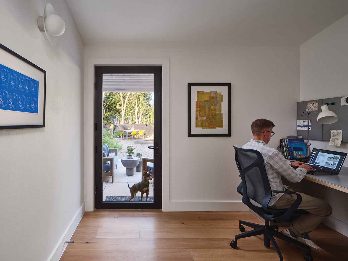 Man working at desk with a glass door to an outdoor patio area.