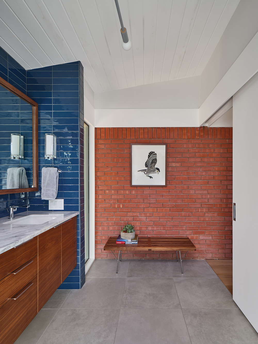 A small bench against a brick wall in a bathroom.