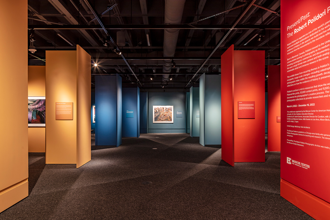 A long view of an art exhibit that sectioned into four sections for their different colored walls.