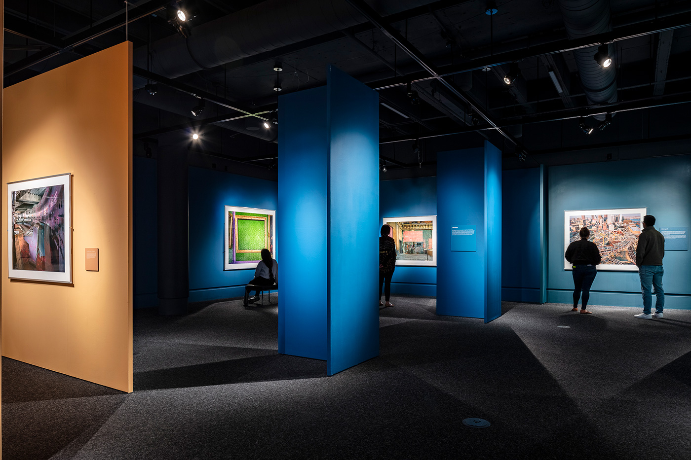 People standing in a blue walled section of an art exhibit.