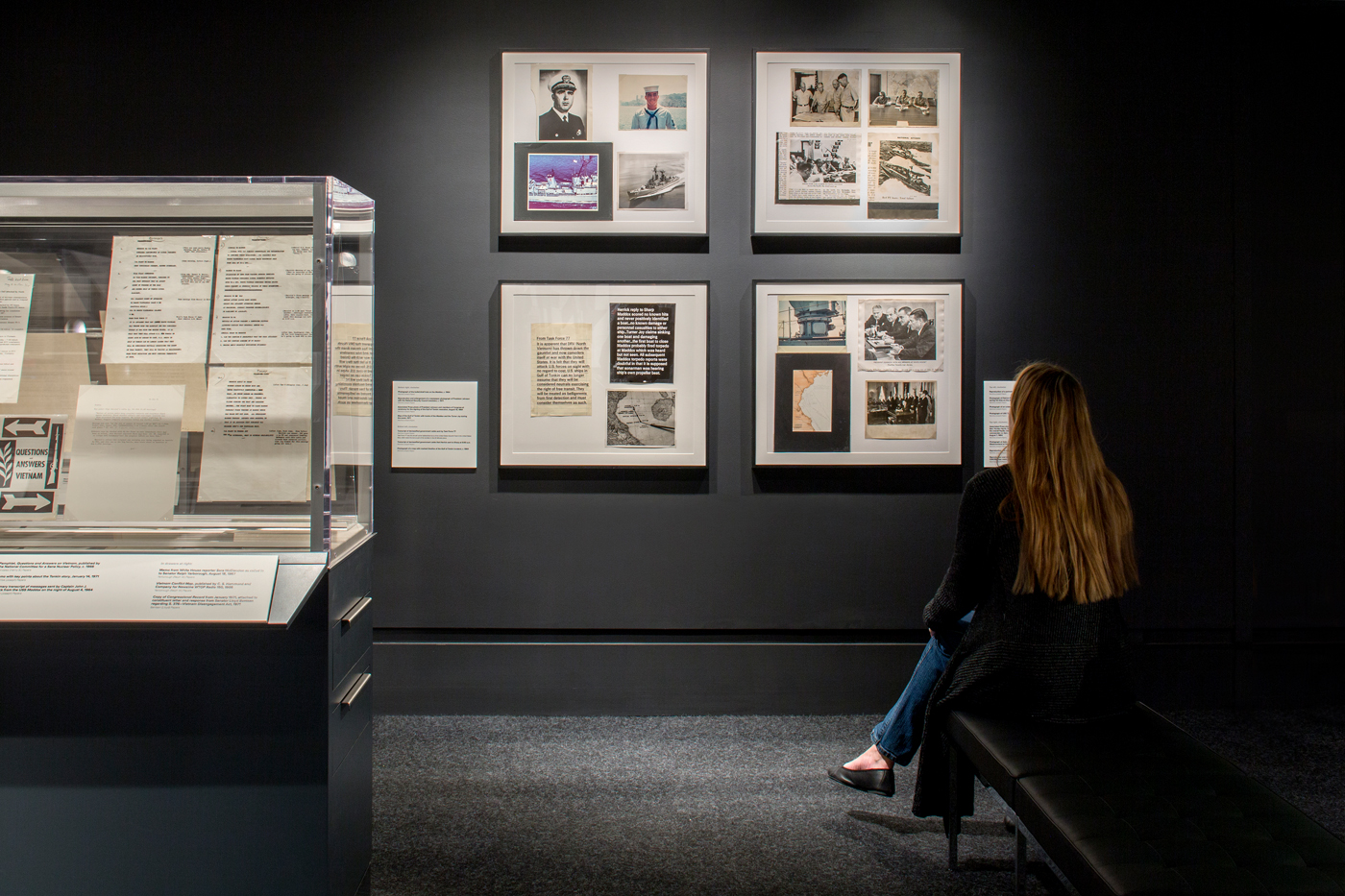 Women sitting looking at historic pictures framed on a museum wall.