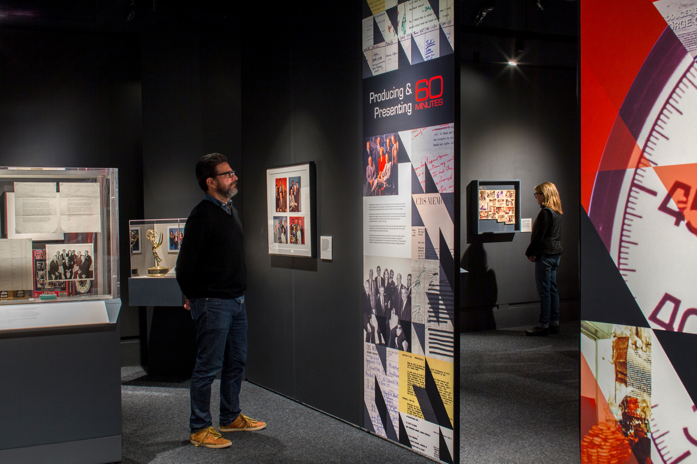 Man standing reading information of exhibit wall.