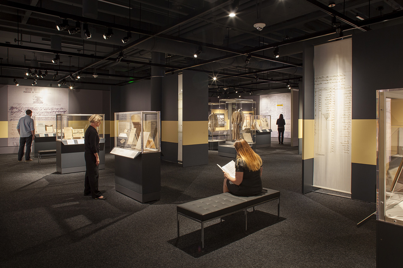 Large dark exhibit room with many standalone halls with people peering in display cases.