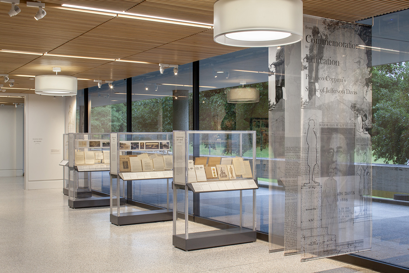 Display cases holding many papers against large windows.