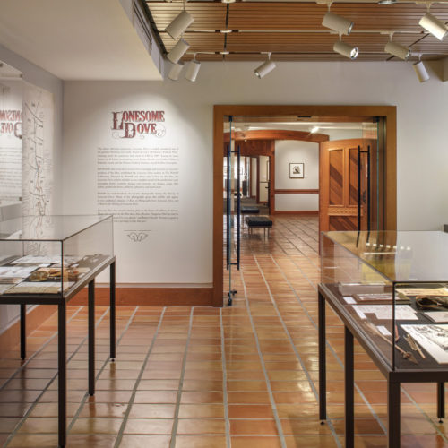 Exhibit room with two glass displays and Writing on the wall that is titles "LONESOME DOVE".
