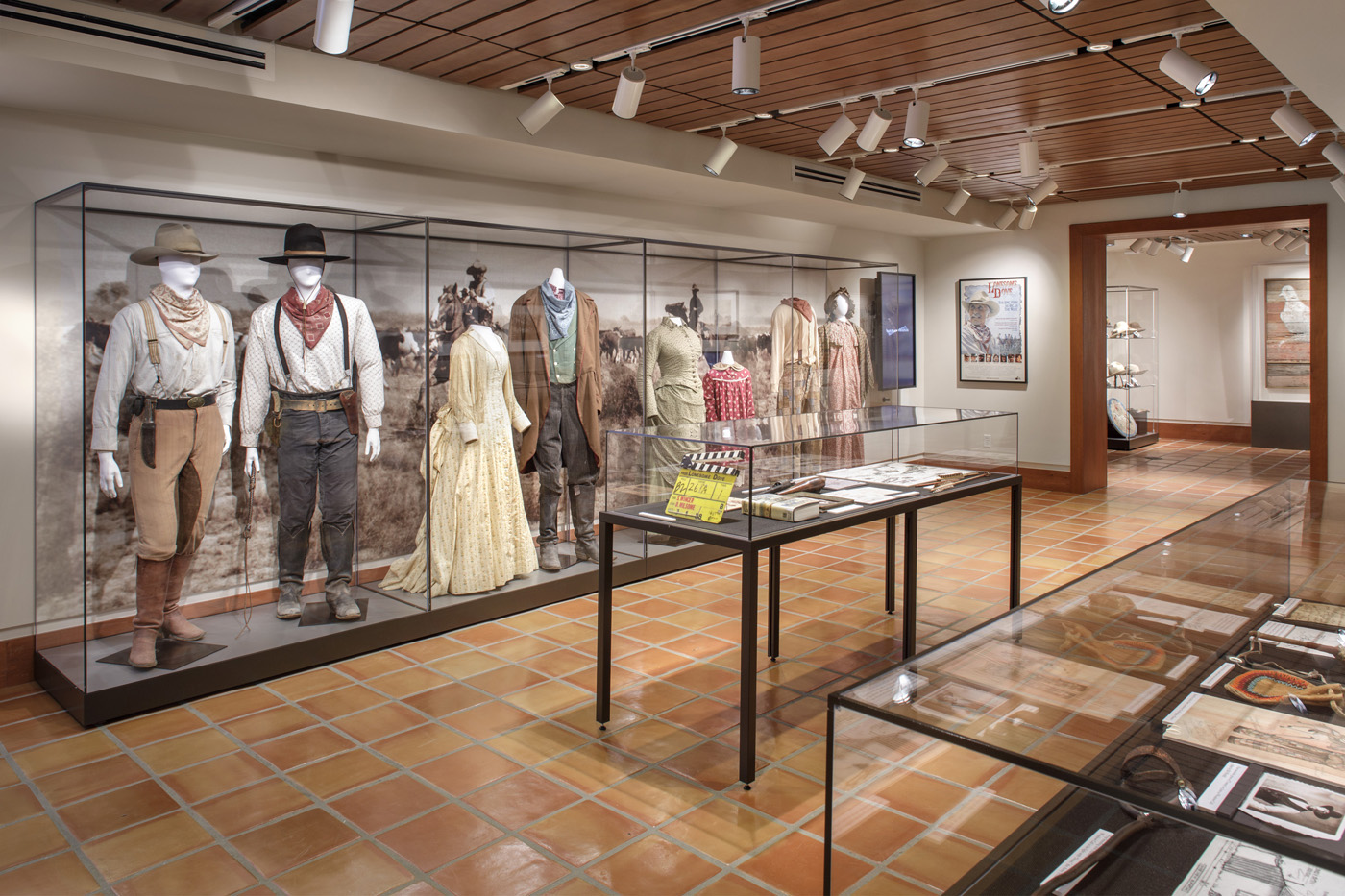 Bright exhibit room with row of mannequins in Historic western attire.
