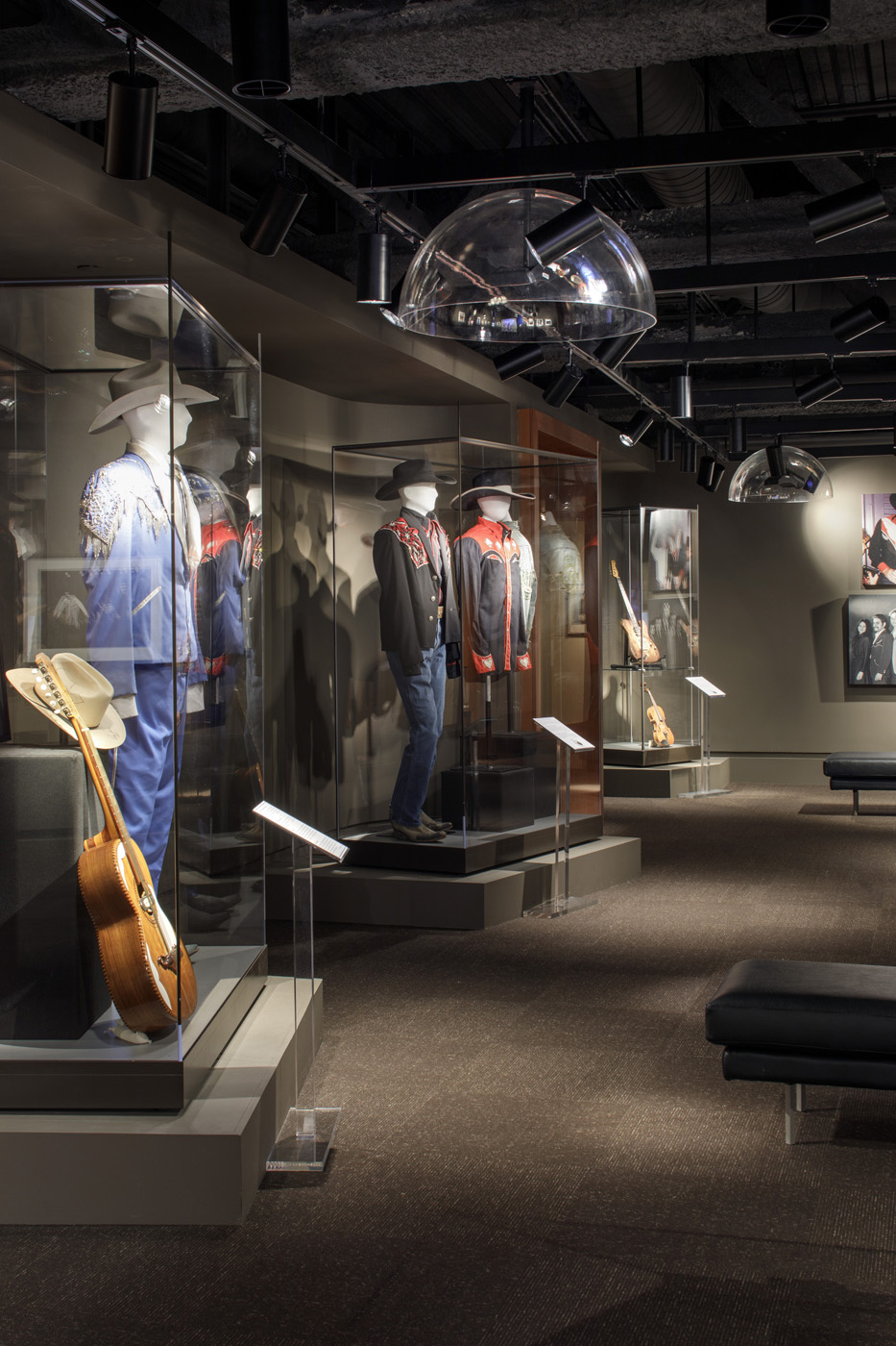 Side view of upright display cases containing clothes and guitars.