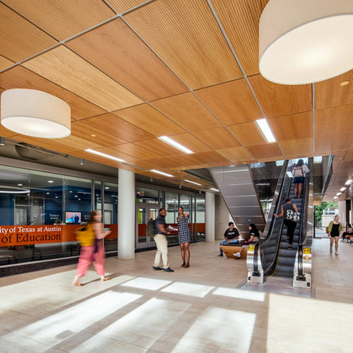 People walking through and chatting in central lobby of the College of Education at University of Texas.