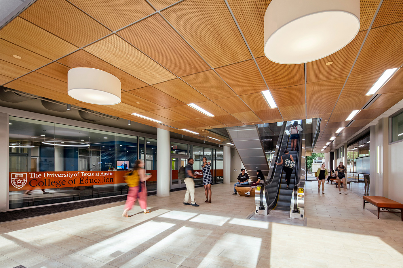 People walking through and chatting in central lobby of the College of Education at University of Texas.