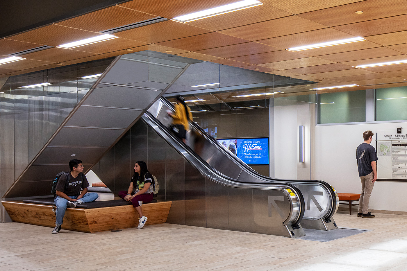 People sitting in the escalators of a modern lobby.