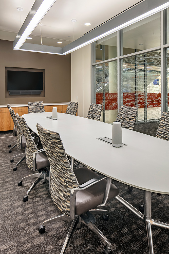 Glass conference room lit by large hanging light.