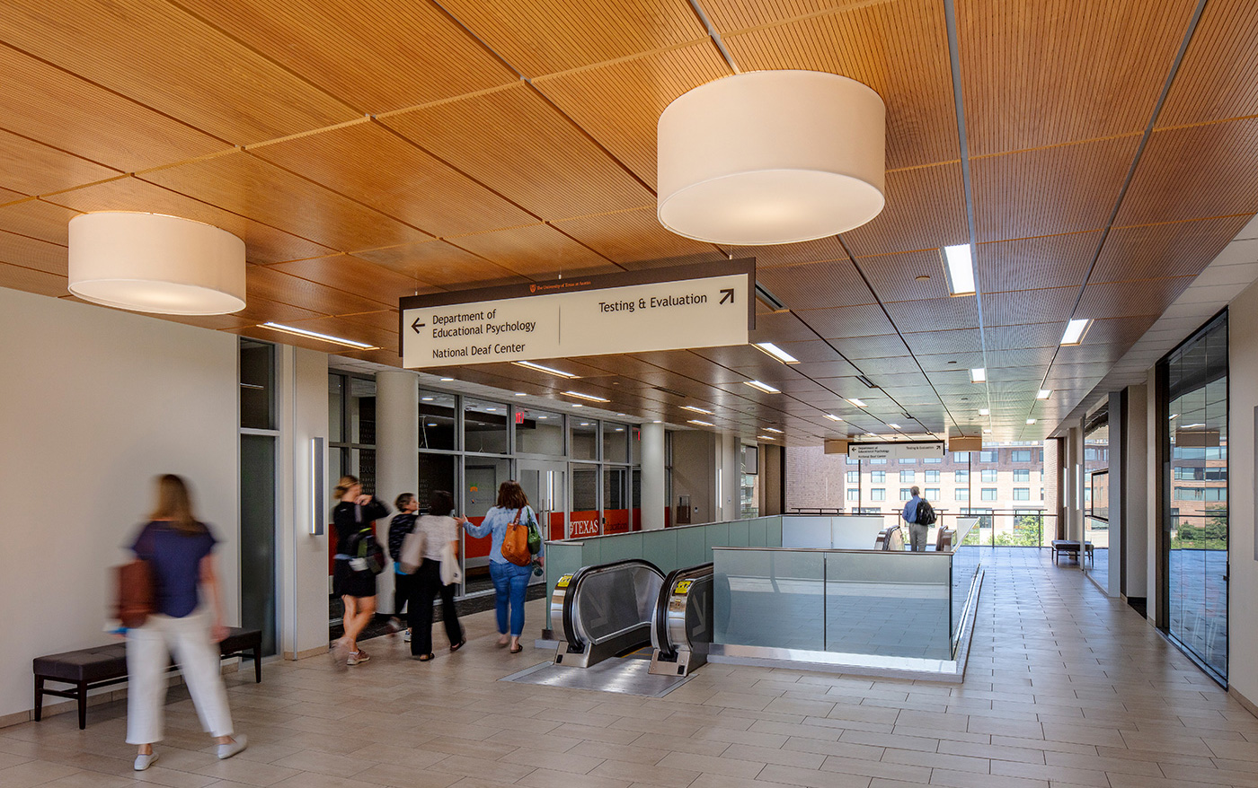 People walking through a building's modern interior escalator space.