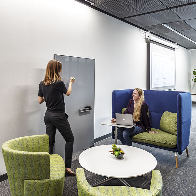 two coworkers talking while in a seating area.