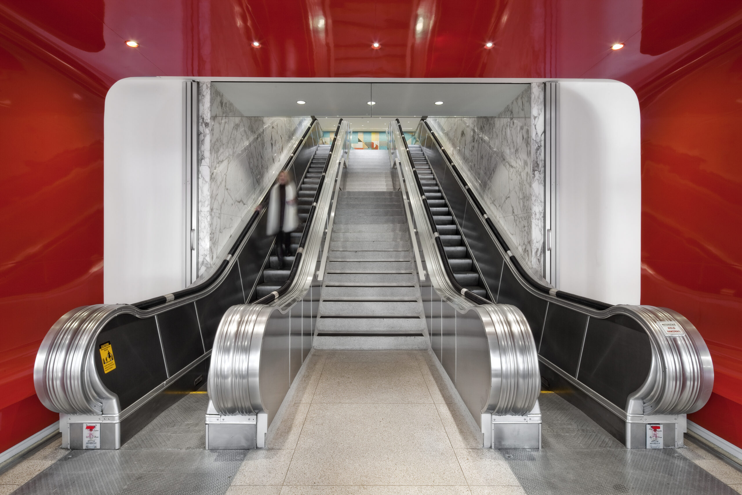 image of McGarrah Jessee building looking into red tunnel entrance opening to stairs and escalators towards geometric mural on back wall