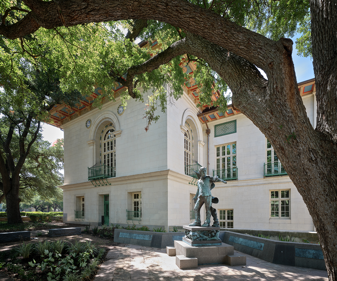 Statue of a man holding a flag in front of a historic stone building.