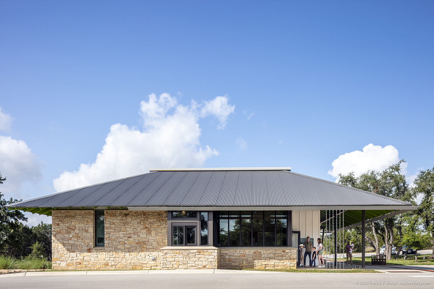 Family walking into a stone building with sloping metal roof.