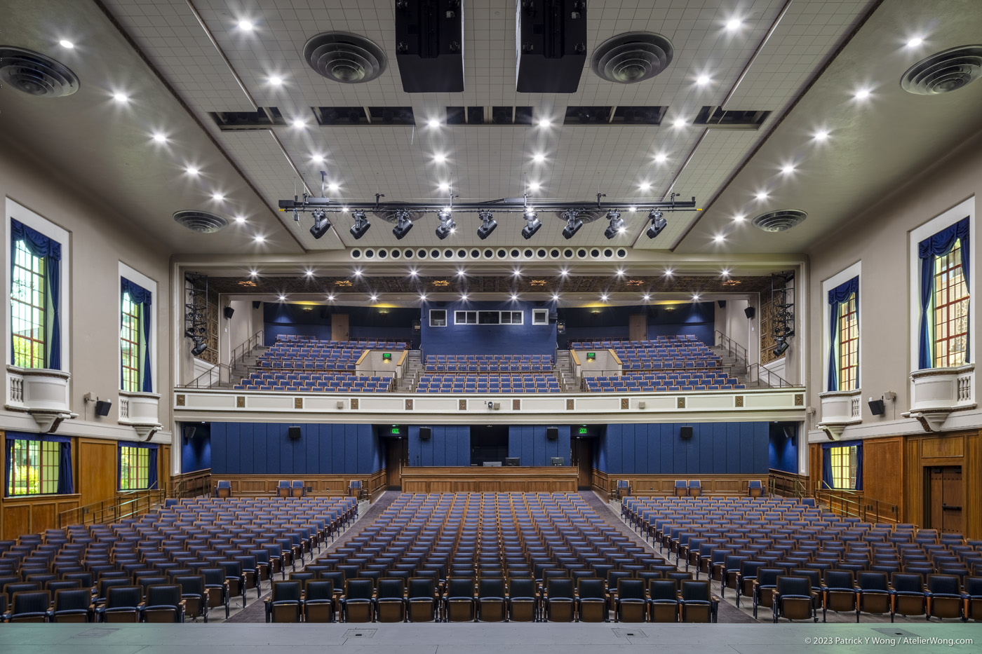Views of an auditorium from the stage, with house lights on and window shades open.