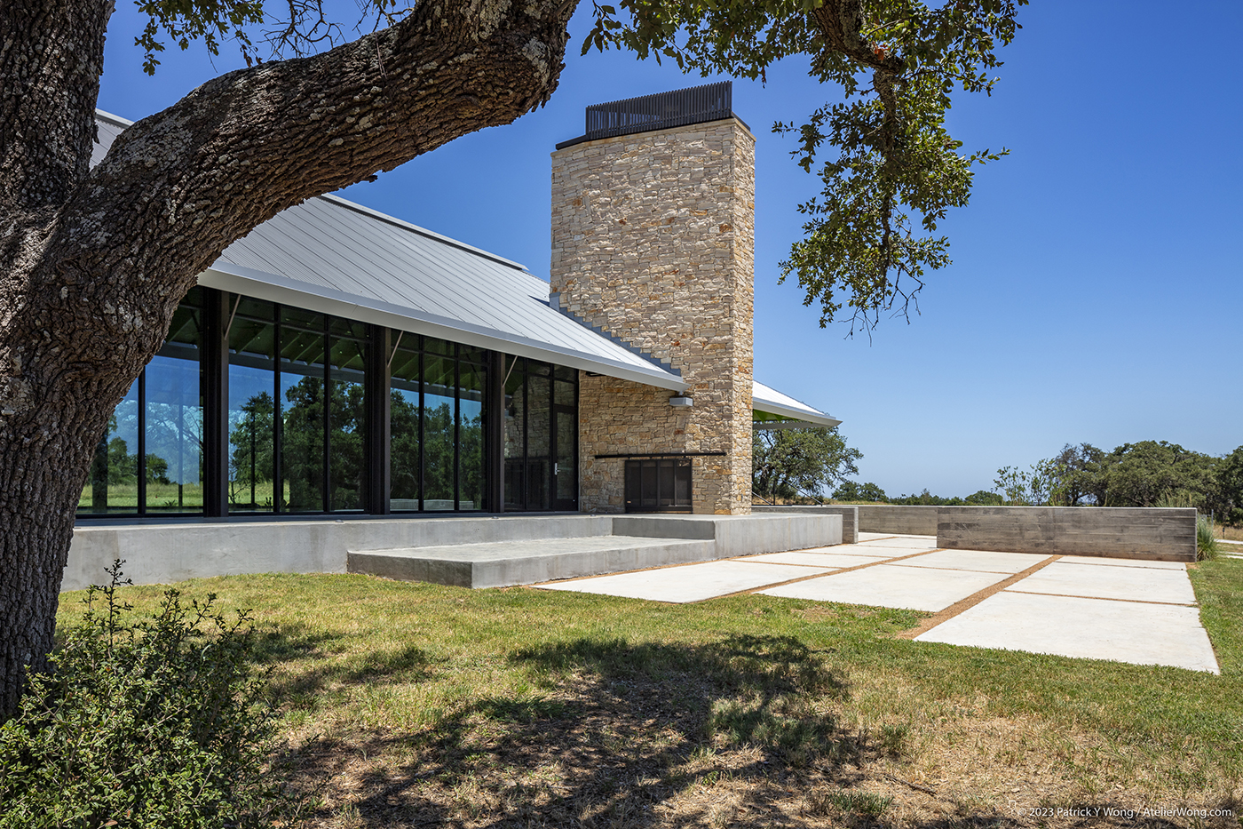 Large concrete pavers leading to a glass-fronted building with a large stone chimney.